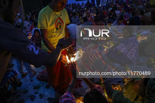 Hindu devotees sit together in front of oil lamps and candles and pray to Lokenath Brahmachari, a Hindu saint and philosopher, as they obser...