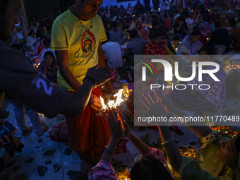 Hindu devotees sit together in front of oil lamps and candles and pray to Lokenath Brahmachari, a Hindu saint and philosopher, as they obser...