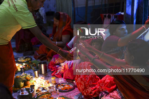 Hindu devotees sit together in front of oil lamps and candles and pray to Lokenath Brahmachari, a Hindu saint and philosopher, as they obser...