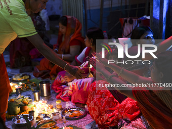 Hindu devotees sit together in front of oil lamps and candles and pray to Lokenath Brahmachari, a Hindu saint and philosopher, as they obser...