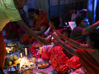 Hindu devotees sit together in front of oil lamps and candles and pray to Lokenath Brahmachari, a Hindu saint and philosopher, as they obser...