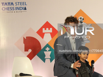 Norway's Magnus Carlsen poses with the world's youngest chess player, India's Anish Sarkar, during the 6th Tata Steel Chess India Rapid & Bl...