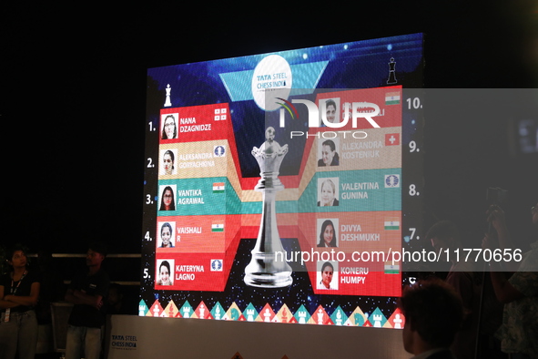 A display board shows the names of women's chess players Aleksandra Goryachkina, Kateryna Lagno, Alexandra Kosteniuk, Nana Dzagnidze, Valent...