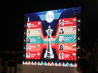 A display board shows the names of women's chess players Aleksandra Goryachkina, Kateryna Lagno, Alexandra Kosteniuk, Nana Dzagnidze, Valent...