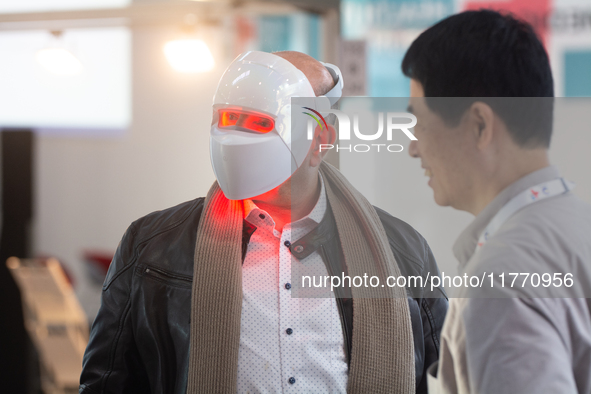 A fairgoer tries out a cosmetics LED face mask at Medica 2024 at the Duesseldorf Exhibition Center in Duesseldorf, Germany, on November 12,...