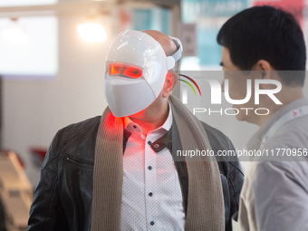 A fairgoer tries out a cosmetics LED face mask at Medica 2024 at the Duesseldorf Exhibition Center in Duesseldorf, Germany, on November 12,...