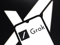 The Grok logo appears on the screen of a smartphone, and in the background, the xAI logo is on the computer screen in Reno, United States, o...