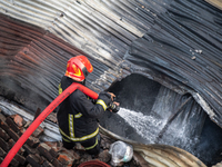 A firefighter works to extinguish flames at a burning shoe factory in a densely populated area of Dhaka, Bangladesh, on November 12, 2024. T...