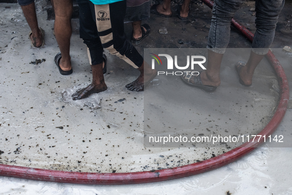 Locals gather around the scene and help firefighters battle the flames at a burning shoe factory in a densely populated area of Dhaka, Bangl...