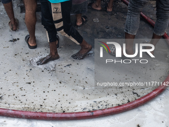 Locals gather around the scene and help firefighters battle the flames at a burning shoe factory in a densely populated area of Dhaka, Bangl...