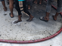 Locals gather around the scene and help firefighters battle the flames at a burning shoe factory in a densely populated area of Dhaka, Bangl...