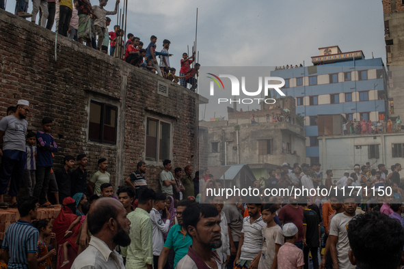 Smoke rises from a burning shoe factory as locals gather on the rooftop of a nearby building in a densely populated area of Dhaka, Banglades...