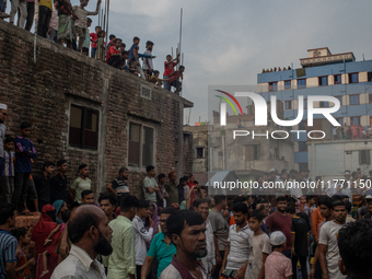 Smoke rises from a burning shoe factory as locals gather on the rooftop of a nearby building in a densely populated area of Dhaka, Banglades...