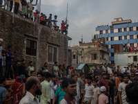 Smoke rises from a burning shoe factory as locals gather on the rooftop of a nearby building in a densely populated area of Dhaka, Banglades...