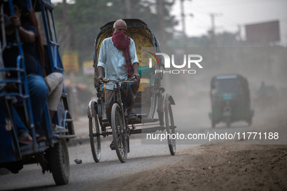 People move through a dusty, busy road in Dhaka, Bangladesh, on November 12, 2024. Dhaka, the overcrowded capital city, ranks 17th among cit...