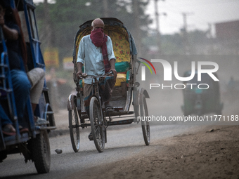 People move through a dusty, busy road in Dhaka, Bangladesh, on November 12, 2024. Dhaka, the overcrowded capital city, ranks 17th among cit...