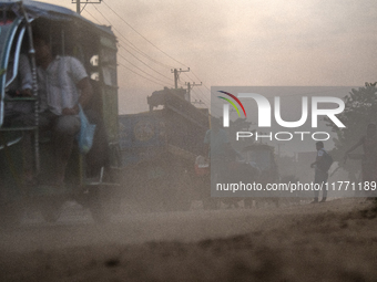 People move through a dusty, busy road in Dhaka, Bangladesh, on November 12, 2024. Dhaka, the overcrowded capital city, ranks 17th among cit...