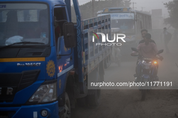 People move through a dusty, busy road in Dhaka, Bangladesh, on November 12, 2024. Dhaka, the overcrowded capital city, ranks 17th among cit...