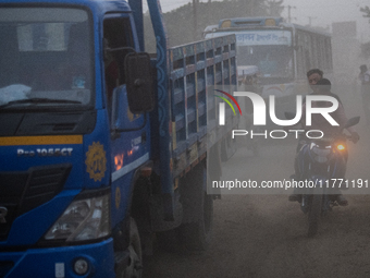 People move through a dusty, busy road in Dhaka, Bangladesh, on November 12, 2024. Dhaka, the overcrowded capital city, ranks 17th among cit...