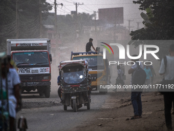 People move through a dusty, busy road in Dhaka, Bangladesh, on November 12, 2024. Dhaka, the overcrowded capital city, ranks 17th among cit...