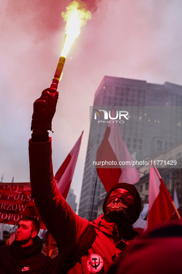 A participant carries a flare while attending Independence March celebrating the 106 anniversary of Poland regaining independence. Warsaw, P...