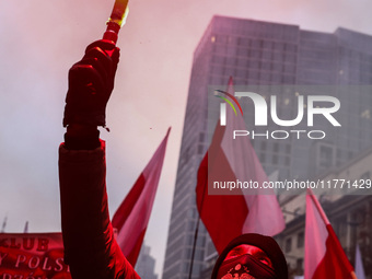 A participant carries a flare while attending Independence March celebrating the 106 anniversary of Poland regaining independence. Warsaw, P...