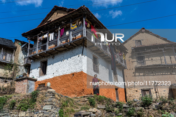 A woman stands in front of her traditional old home in the village of Makwanpur, Nepal, on November 12, 2024. 