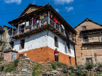 A woman stands in front of her traditional old home in the village of Makwanpur, Nepal, on November 12, 2024. (