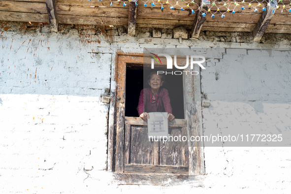 A woman watches through a traditional window in the village of Makwanpur, Nepal, on November 12, 2024. 