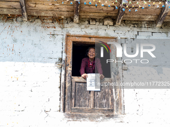 A woman watches through a traditional window in the village of Makwanpur, Nepal, on November 12, 2024. (