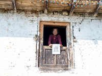 A woman watches through a traditional window in the village of Makwanpur, Nepal, on November 12, 2024. (