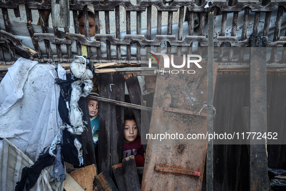 Displaced Palestinian children view the site of an Israeli strike on a tent housing displaced people in Deir el-Balah, Gaza Strip, on Novemb...