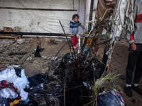 Displaced Palestinian children view the site of an Israeli strike on a tent housing displaced people in Deir el-Balah, Gaza Strip, on Novemb...