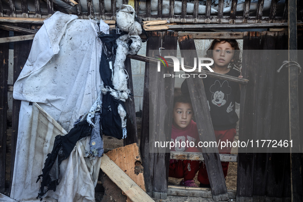 Displaced Palestinian children view the site of an Israeli strike on a tent housing displaced people in Deir el-Balah, Gaza Strip, on Novemb...