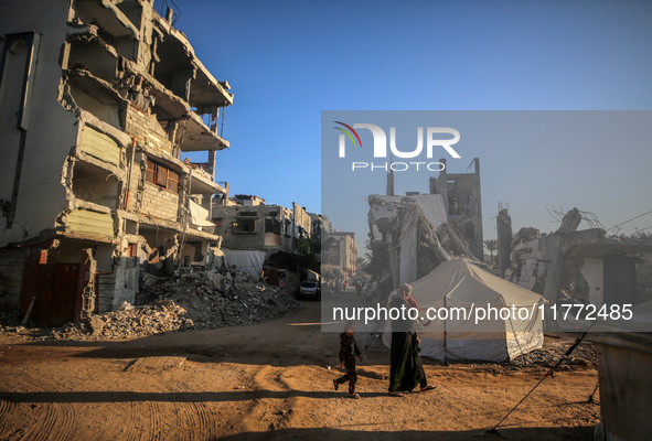 A Palestinian woman carries a child as they walk past the rubble of houses destroyed in previous strikes during the Israeli military offensi...