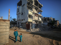 Palestinian children walk past the rubble of houses destroyed in previous strikes during the Israeli military offensive, amid the Israel-Ham...