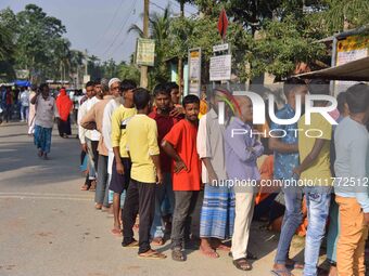 Voters wait in a queue at a polling station to cast votes during the Samaguri assembly constituency bypoll in Nagaon district, Assam, India,...