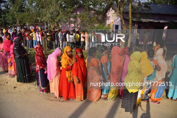 Voters wait in a queue at a polling station to cast votes during the Samaguri assembly constituency bypoll in Nagaon district, Assam, India,...