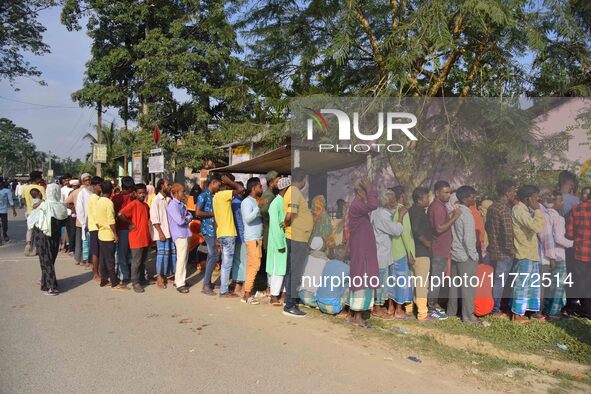 Voters wait in a queue at a polling station to cast votes during the Samaguri assembly constituency bypoll in Nagaon district, Assam, India,...