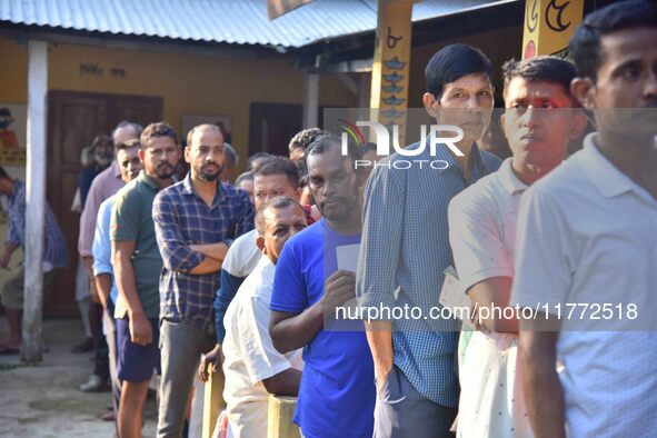 Voters wait in a queue at a polling station to cast votes during the Samaguri assembly constituency bypoll in Nagaon district, Assam, India,...