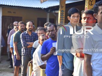 Voters wait in a queue at a polling station to cast votes during the Samaguri assembly constituency bypoll in Nagaon district, Assam, India,...