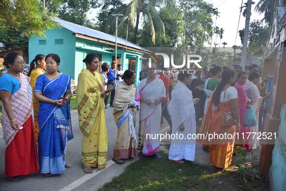 Voters wait in a queue at a polling station to cast votes during the Samaguri assembly constituency bypoll in Nagaon district, Assam, India,...