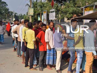 Voters wait in a queue at a polling station to cast votes during the Samaguri assembly constituency bypoll in Nagaon district, Assam, India,...