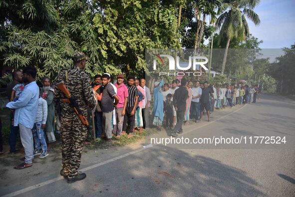 Voters wait in a queue at a polling station to cast votes during the Samaguri assembly constituency bypoll in Nagaon district, Assam, India,...