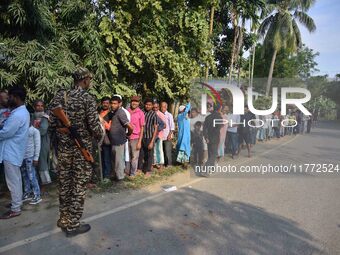 Voters wait in a queue at a polling station to cast votes during the Samaguri assembly constituency bypoll in Nagaon district, Assam, India,...