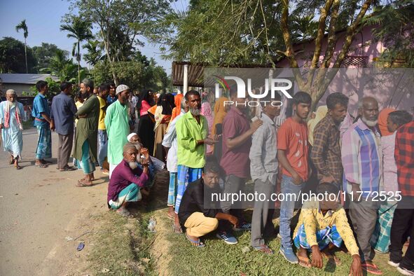 Voters wait in a queue at a polling station to cast votes during the Samaguri assembly constituency bypoll in Nagaon district, Assam, India,...