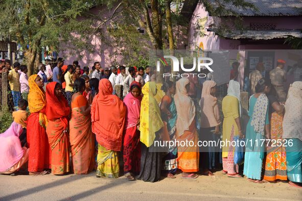 Voters wait in a queue at a polling station to cast votes during the Samaguri assembly constituency bypoll in Nagaon district, Assam, India,...