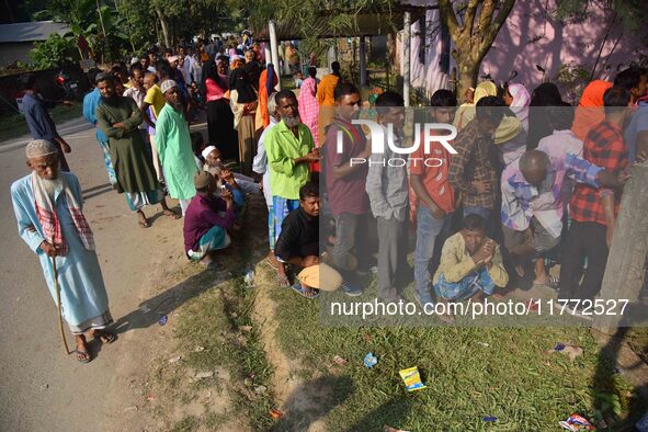 Voters wait in a queue at a polling station to cast votes during the Samaguri assembly constituency bypoll in Nagaon district, Assam, India,...