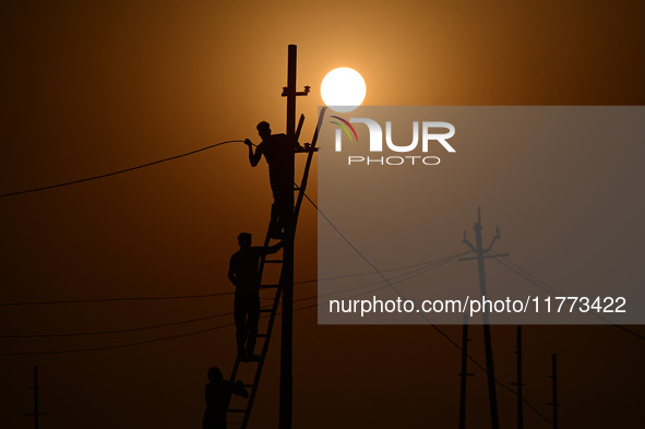 An electrician adjusts cables set up temporarily on the banks of the Sangam area in Prayagraj, India, on November 9, 2024, ahead of the upco...