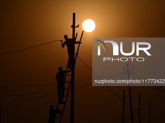 An electrician adjusts cables set up temporarily on the banks of the Sangam area in Prayagraj, India, on November 9, 2024, ahead of the upco...